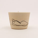 Ceramic candle holder with reclining abstract figure illustration