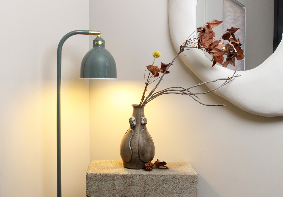 Emily and Company ceramic vase styled under a lamp in a modern interior
