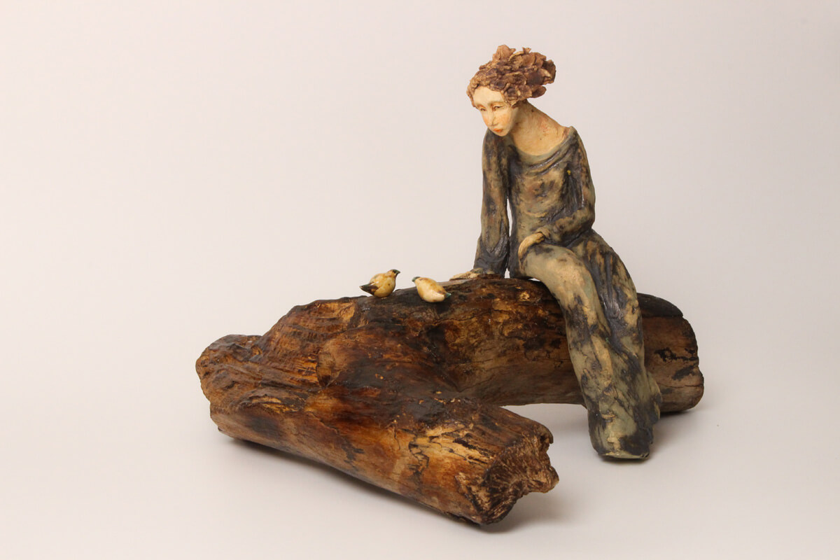Front close view of Keeper of Flight ceramic sculpture with seated figure and birds