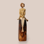 Poised ceramic sculpture main image with seated female figure on pedestal